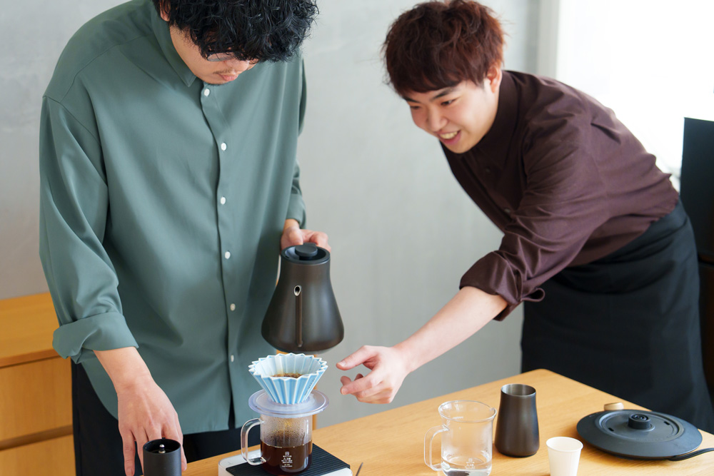 先生がハンドドリップする生徒を手伝っているところ